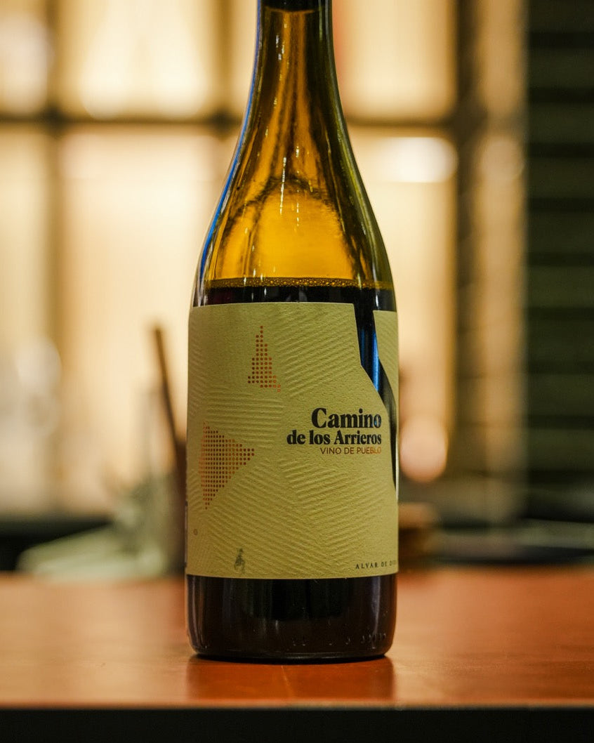 Wine by alvar de dios, 'Camino de los Arrieros' on a wooden surface with a blurred background.